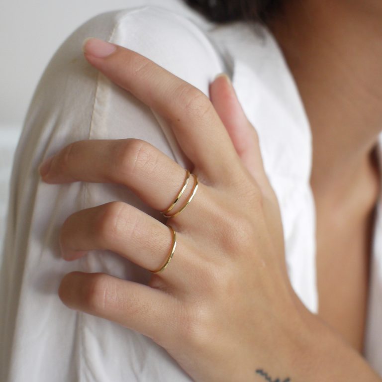 mulher usando conjunto de três anéis básicos e minimalistas feitos à mão em ouro 18k de aro polido e martelado