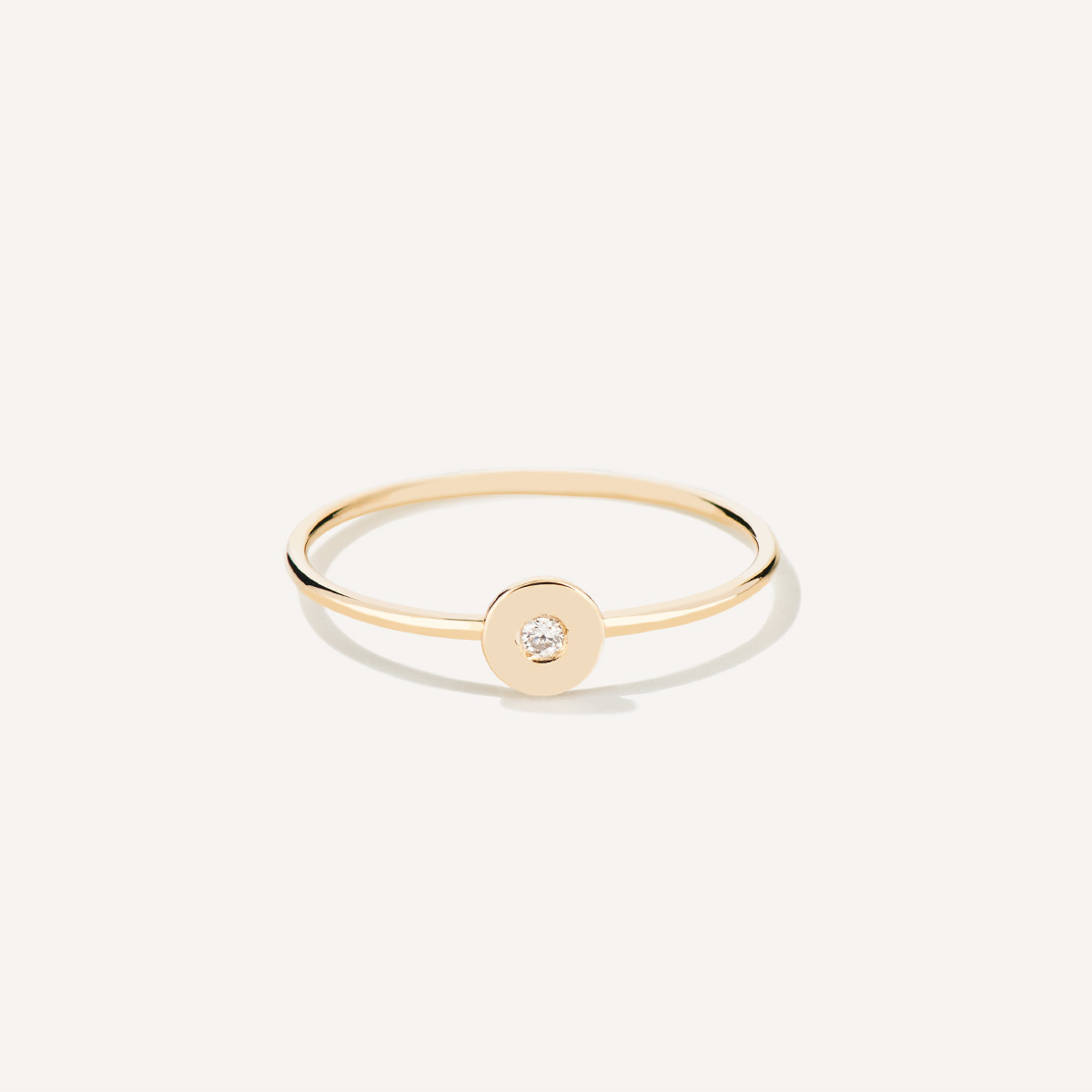 Anel de aro fino minimalista feito a mão em ouro 18k com diamante no centro sobre tecido branco