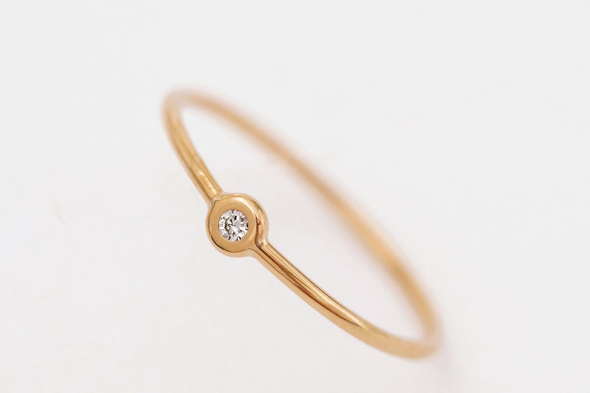 Anel de aro fino minimalista feito a mão em ouro 18k com diamante sobre fundo branco