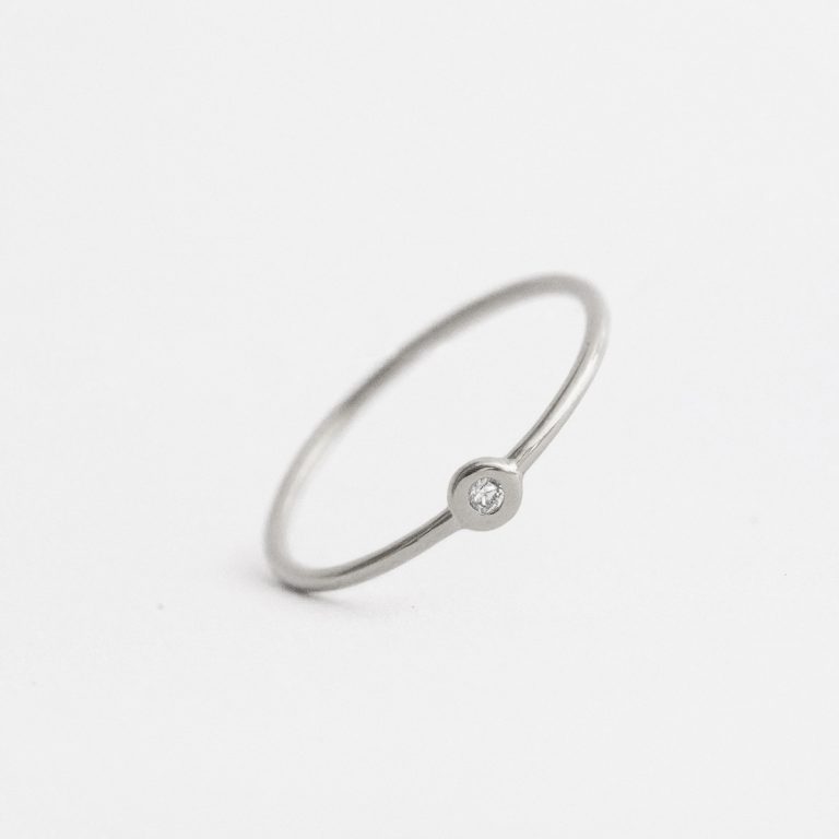 Anel de aro fino minimalista feito a mão em ouro 18k com diamante sobre fundo branco