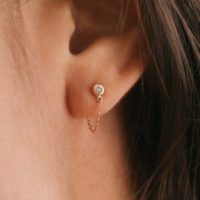 Brinco minimalista feito a mão em ouro 18k com diamante na ponta e corrente ligando a tarraxa