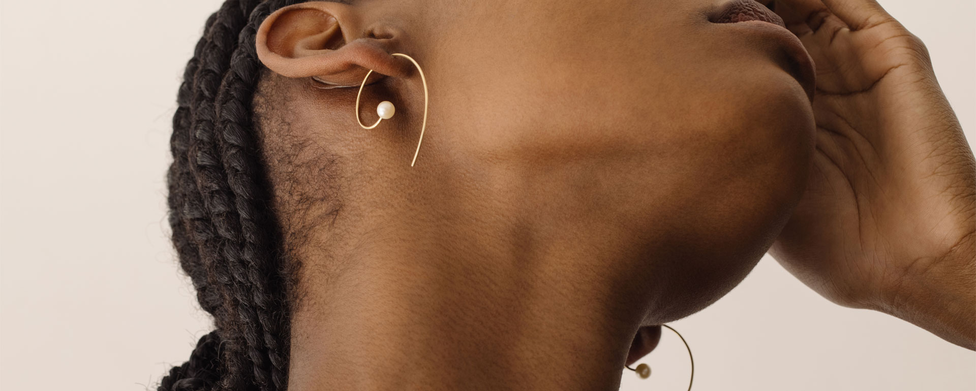 Modelo negra vestindo brinco caracol de ouro amarelo 18k com uma pérola