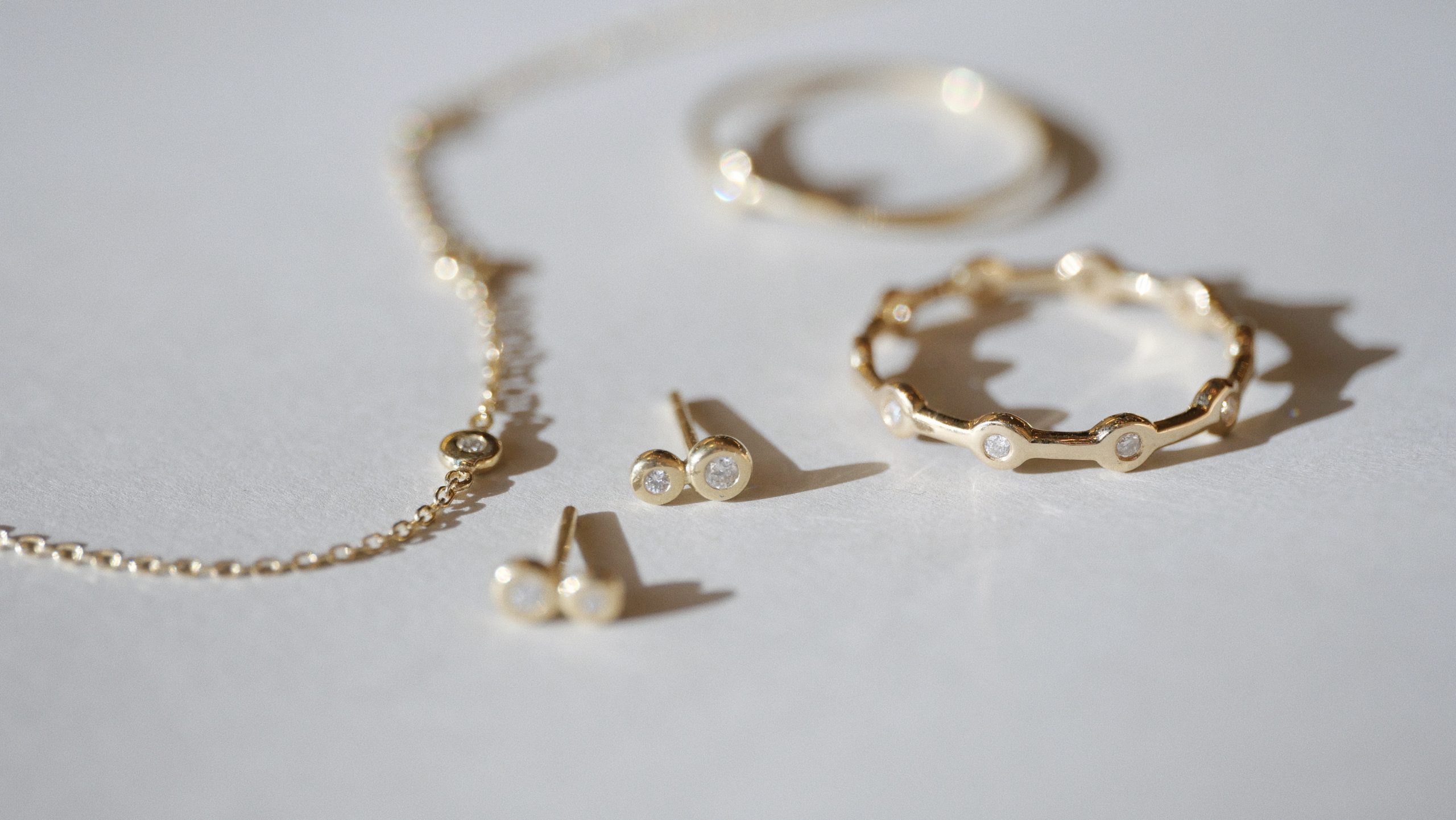 pulseira, brinco e anel sobre fundo cinza claro
