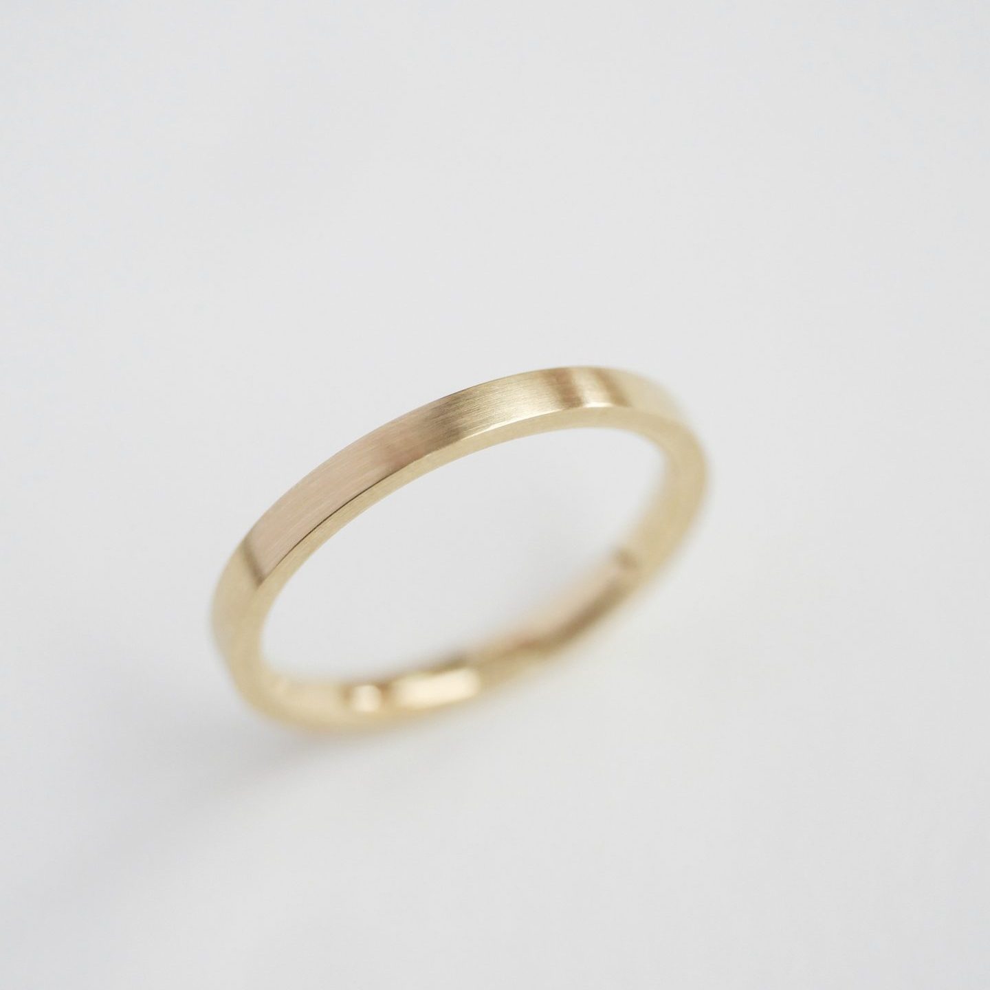 aliança de casamento feita à mão em ouro 18k e minimalista sobre fundo branco