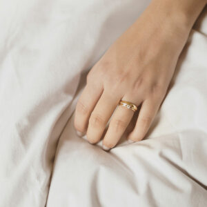Mão feminina usando aliança de 4mm minimalista feita a mão em ouro 18k com diamantes para casamentos