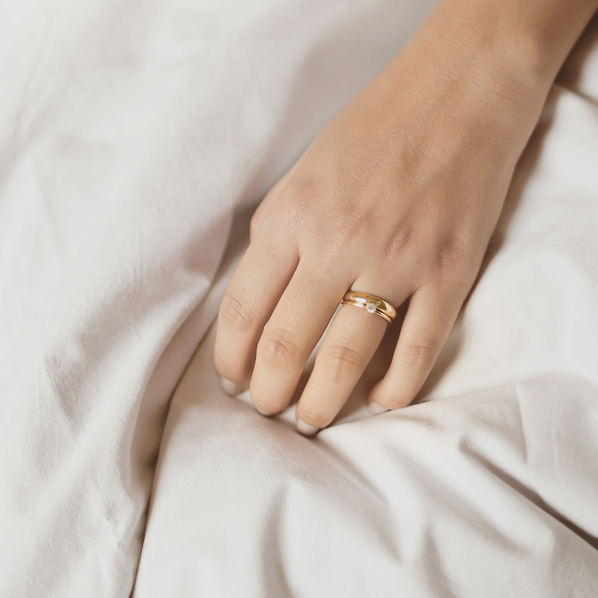 Mão feminina usando aliança de 4mm minimalista feita a mão em ouro 18k com diamantes para casamentos