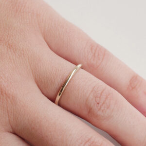 Mulher usando Aliança meia cana com aro de 1,5mm fina minimalista feita a mão em ouro 18k para casamentos sobre fundo branco