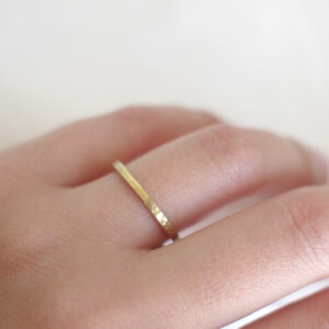 Mão feminina usando Aliança minimalista martelada feita a mão em ouro 18k sobre fundo branco