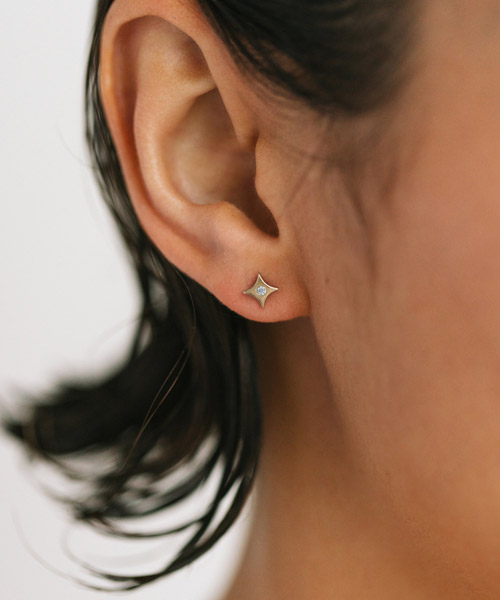 mulher usando brinco em formato de estrela feito a mão em ouro 18k com diamante no centro