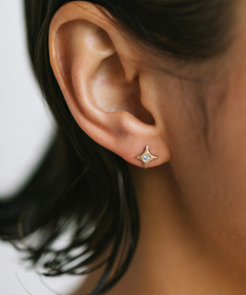 mulher usando brinco em formato de estrela feito a mão em ouro 18k com diamante no centro