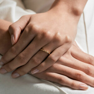 mão feminina com aliança de casamento feita à mão em ouro 18k que o par forma um coração minimalista