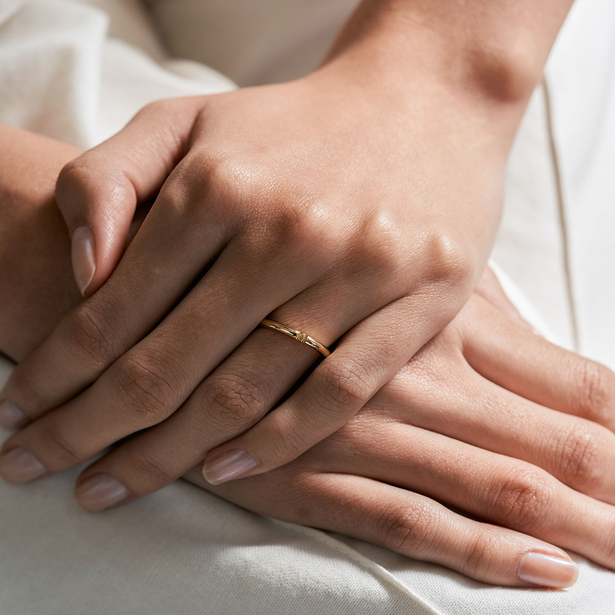 mão feminina com aliança de casamento feita à mão em ouro 18k que o par forma um coração minimalista