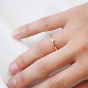 Mulher usando aliança minimalista feita a mão em ouro 18k com encaixe de diamante para casamentos