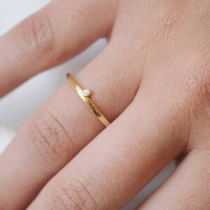 Mulher usando aliança minimalista feita a mão em ouro 18k com encaixe de diamante para casamentos