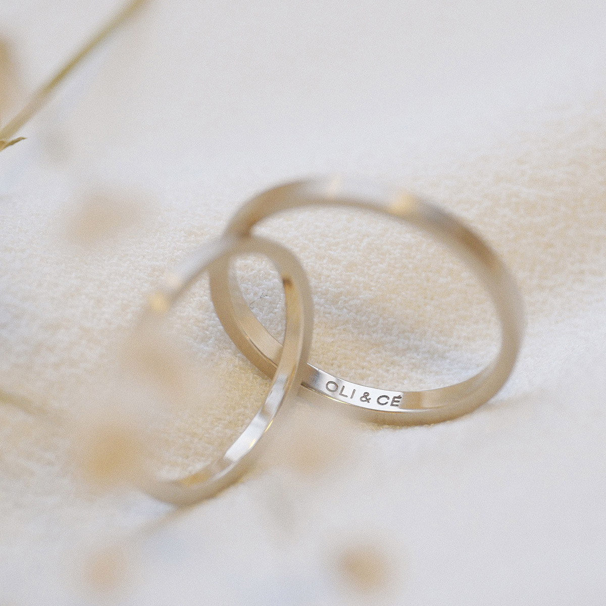 par de alianças de casamento feita à mão em ouro 18k e diamante central de 3 pontos minimalista e gravação sobre fundo branco