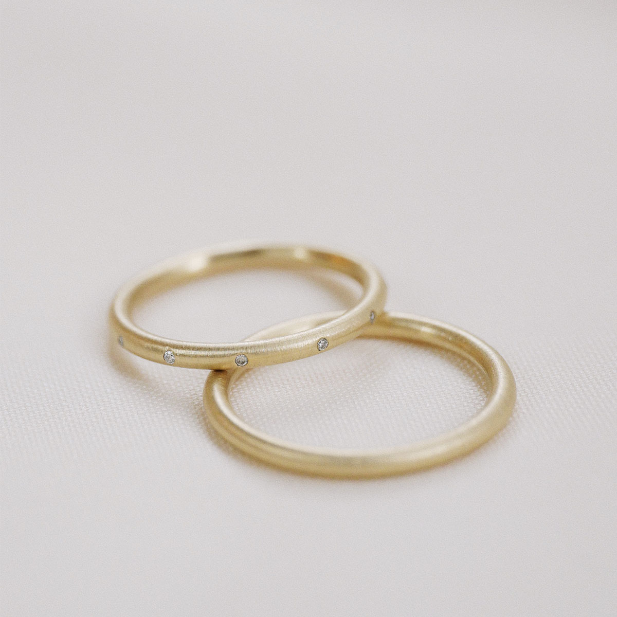 Par de alianças de aro redondo 1,8mm minimalistas feitas a mão em ouro 18k para casamentos sobre fundo branco