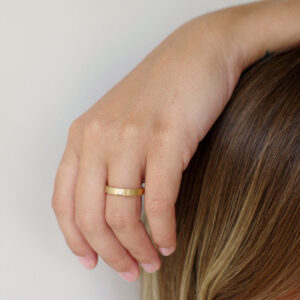 mão feminina com aliança de casamento feita a mão em ouro 18k e diamante central de 3 pontos minimalista