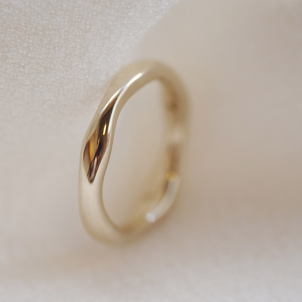 Aliança irregular orgânica minimalista feita a mão em ouro 18k para casamentos sobre tecido