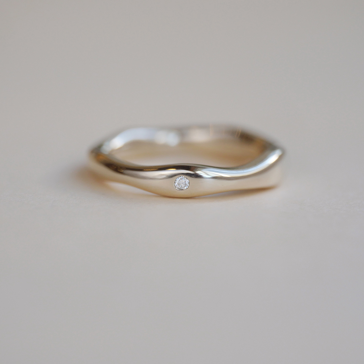 Aliança irregular orgânica minimalista feita a mão em ouro 18k para casamentos sobre fundo branco