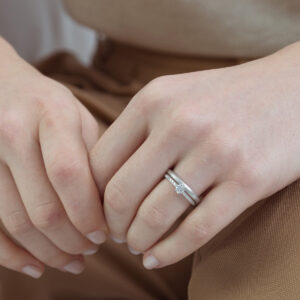 Mão feminina usando anel solitário cravejado minimalista de diamantes em ouro 18k