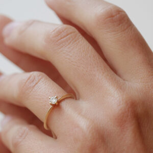 Mulher usando anel solitário minimalista com diamantes de 13p em ouro 18k