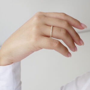 Mulher de blusa branca usando Aliança cravejada minimalista feita a mão em ouro 18k para casamentos sobre fundo branco