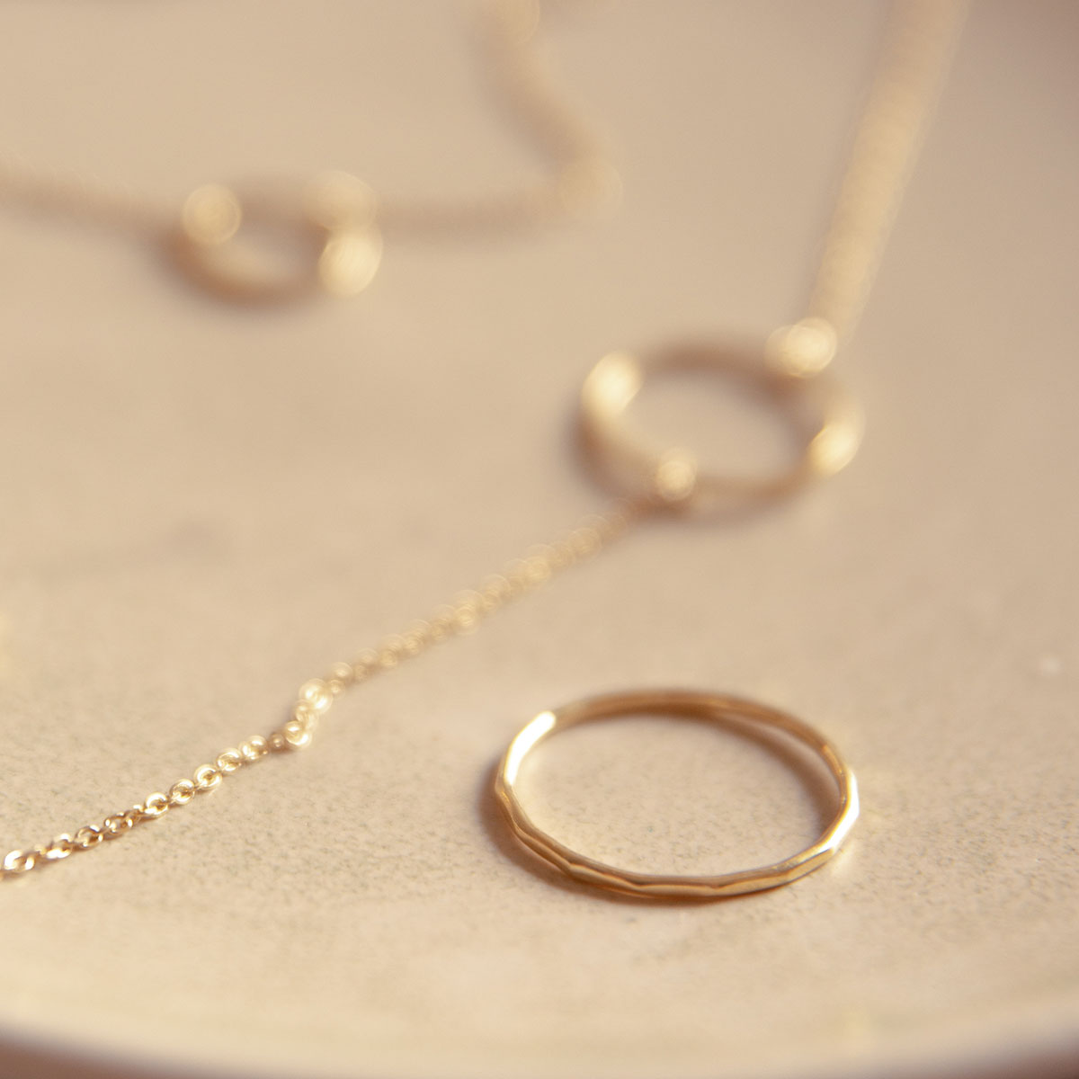 Aliança minimalista martelada feita a mão em ouro 18k com pulseiras sobre prato de cerâmica