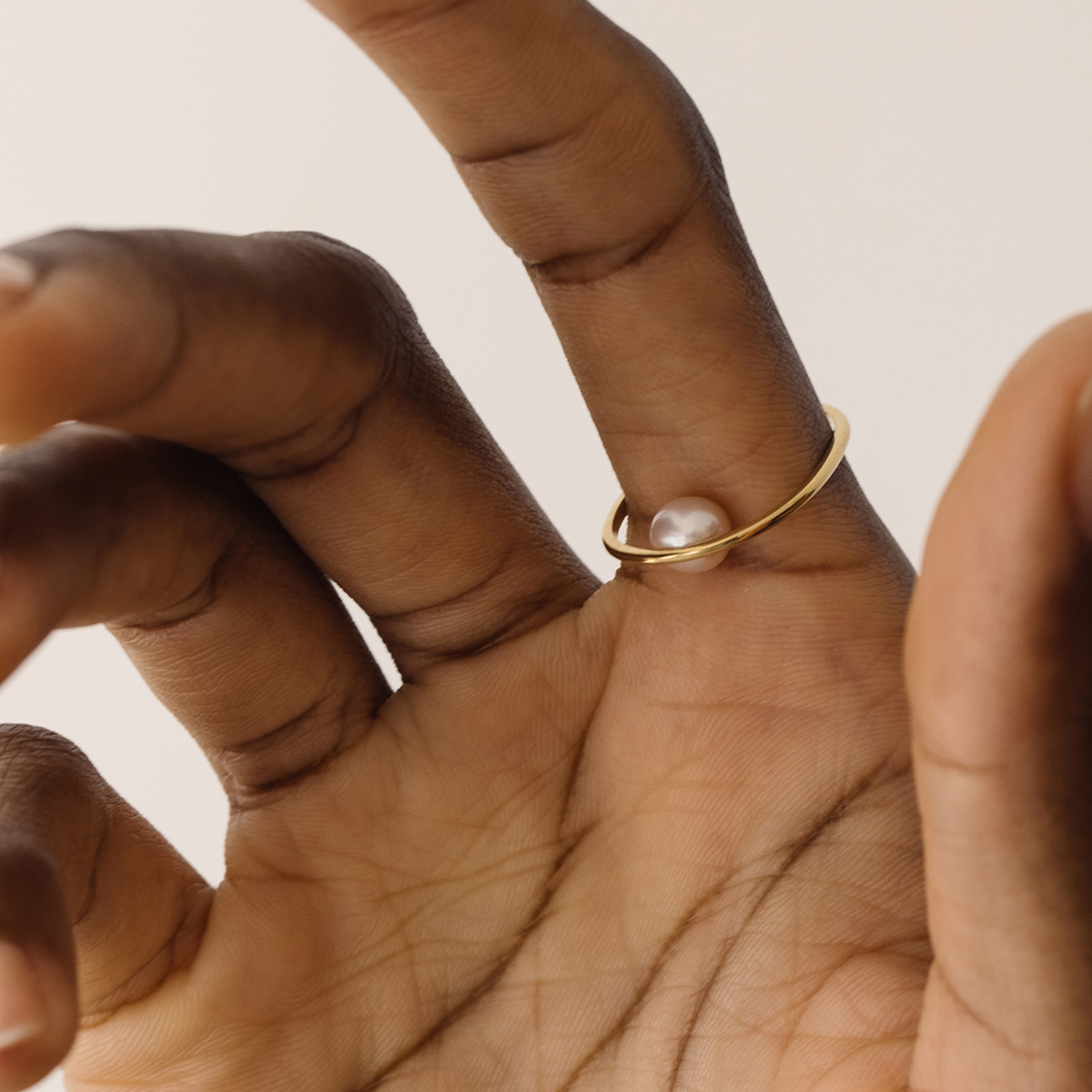 Mulher usando Anel minimalista de formato oval com pérola natural feito a mão em ouro 18k