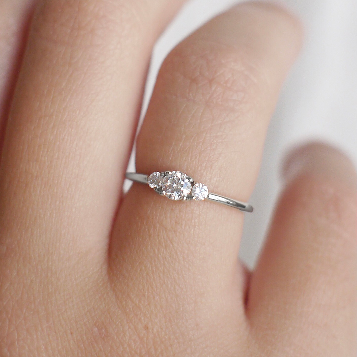 Mão feminina usando Anel de noivado em ouro 18k com diamante de 18p minimalista feito a mão