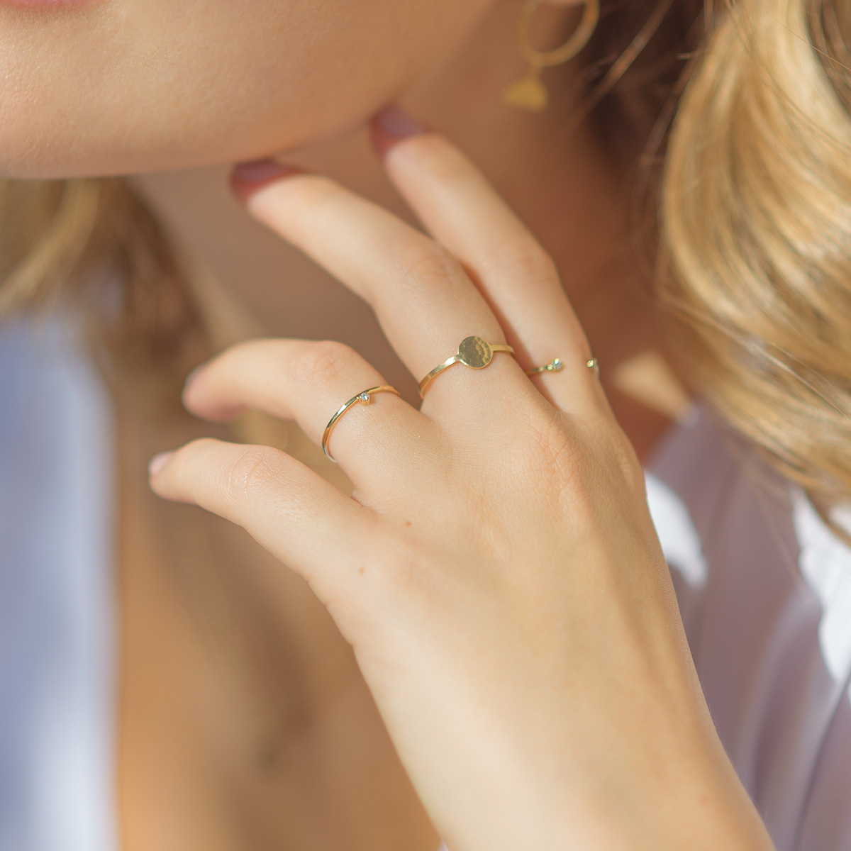 Mão feminina usando anel martelado em ouro 18k com diamante minimalista para noivado