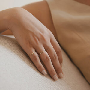 Mão feminina usando anel martelado em ouro 18k com diamante minimalista