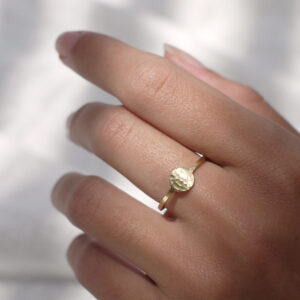 Mão feminina usando Anel minimalista feito a mão em ouro 18k com círculo martelado na frente
