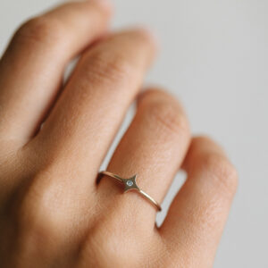 Mão vestindo Anel minimalista feito a mão em ouro 18k com estrela e diamante no centro