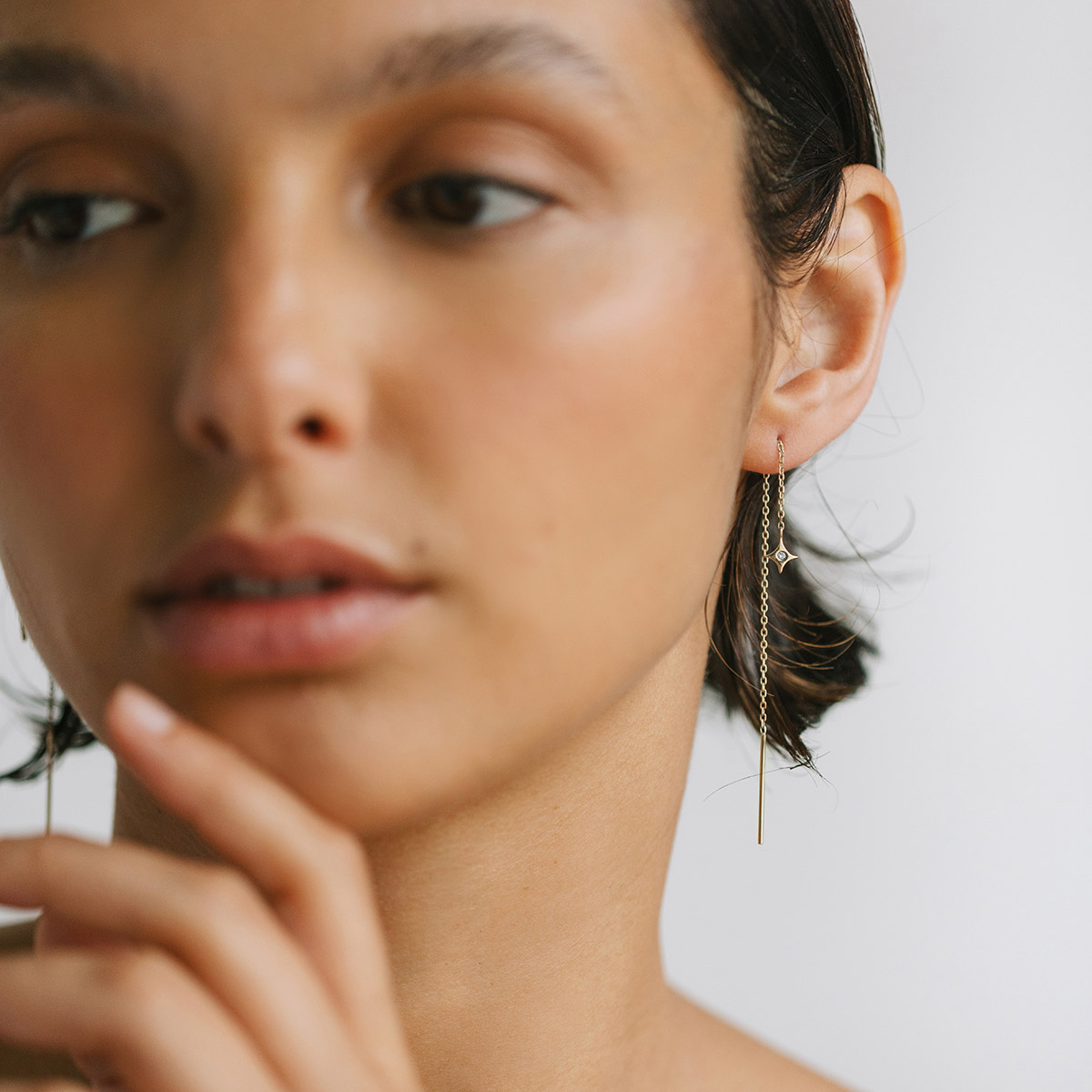Mulher usando Brinco de estrela com diamante minimalista feito a mão com corrente em ouro 18k