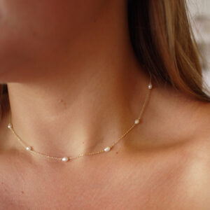 Mulher usando choker minimalista feita a mão em ouro 18k com 10 mini pérolas naturais