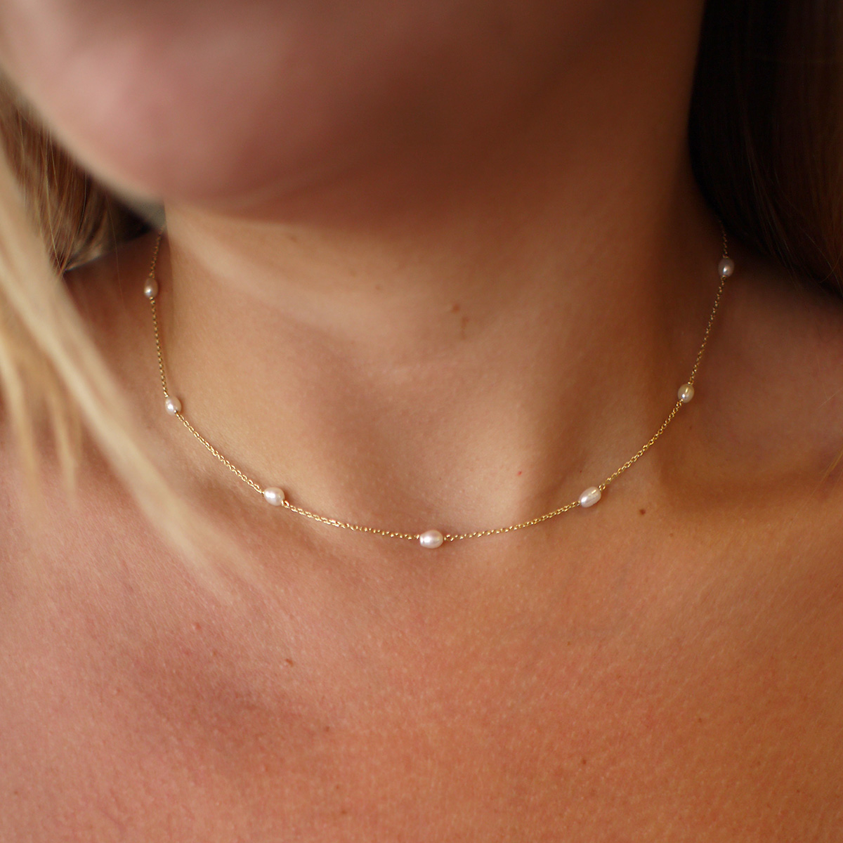 Mulher usando choker minimalista feita a mão em ouro 18k com 10 mini pérolas naturais