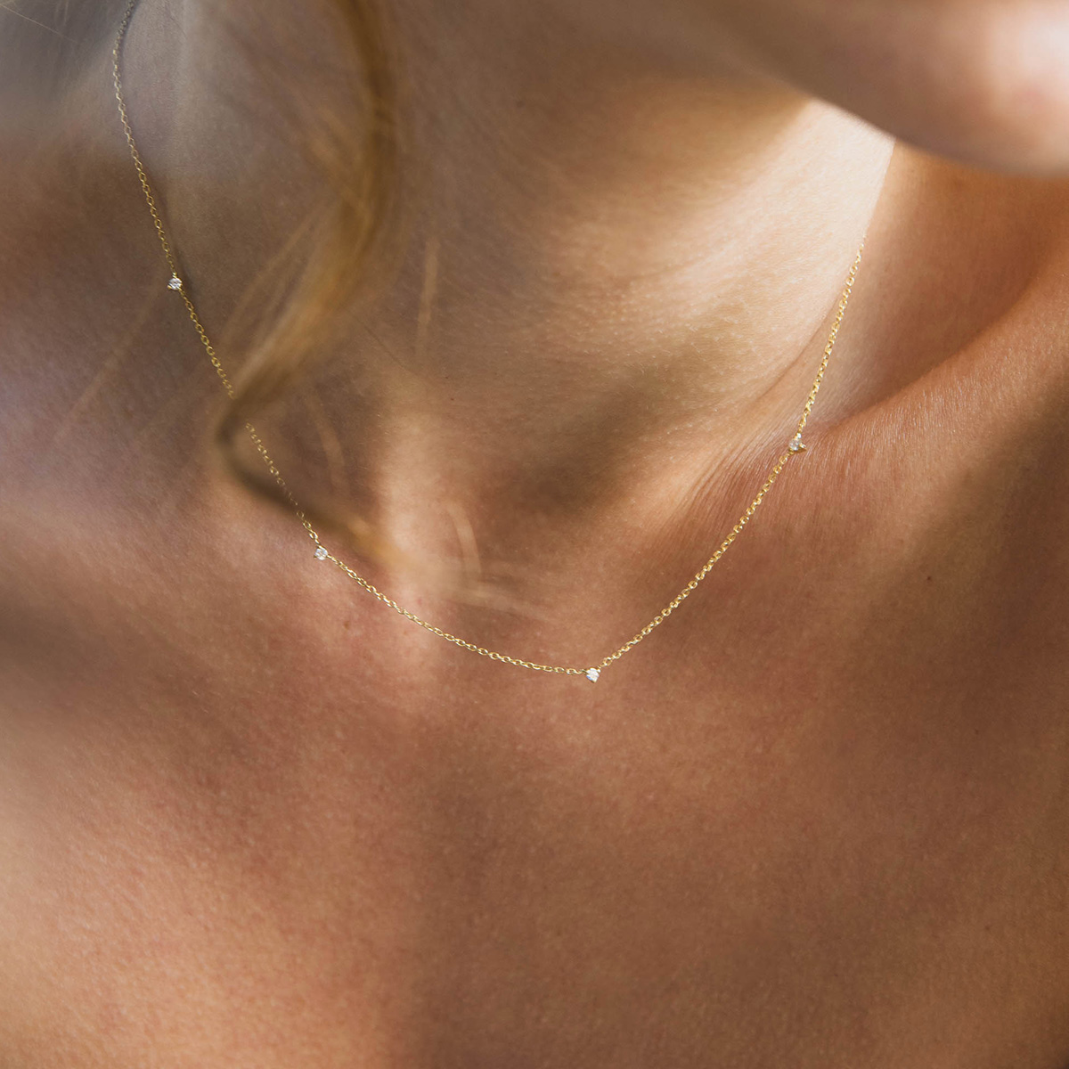 Mulher usando colar delicado e minimalista feito a mão em ouro 18k com pequenos diamantes
