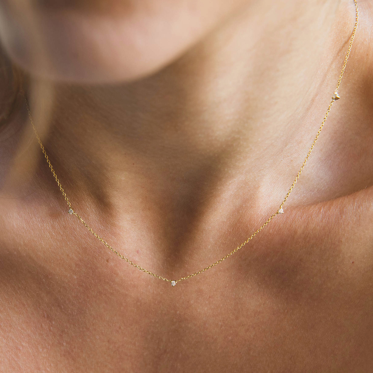 Mulher usando colar delicado e minimalista feito a mão em ouro 18k com pequenos diamantes
