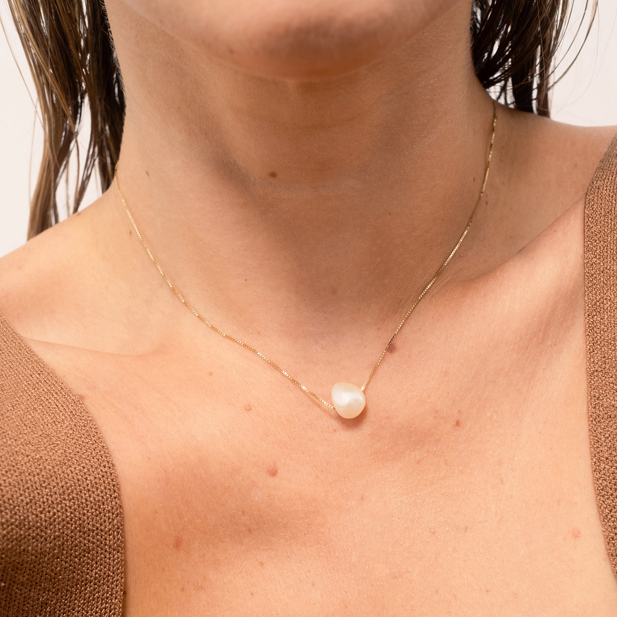 Mulher usando colar minimalista feito a mão com corrente em ouro 18k e pérola natural orgânica