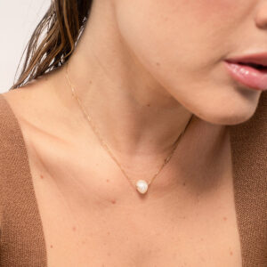 Mulher usando colar minimalista feito a mão com corrente em ouro 18k e pérola natural orgânica