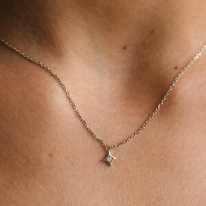Mulher usando colar feito a mão em ouro 18k com pingente de estrela com diamante no centro minimalista