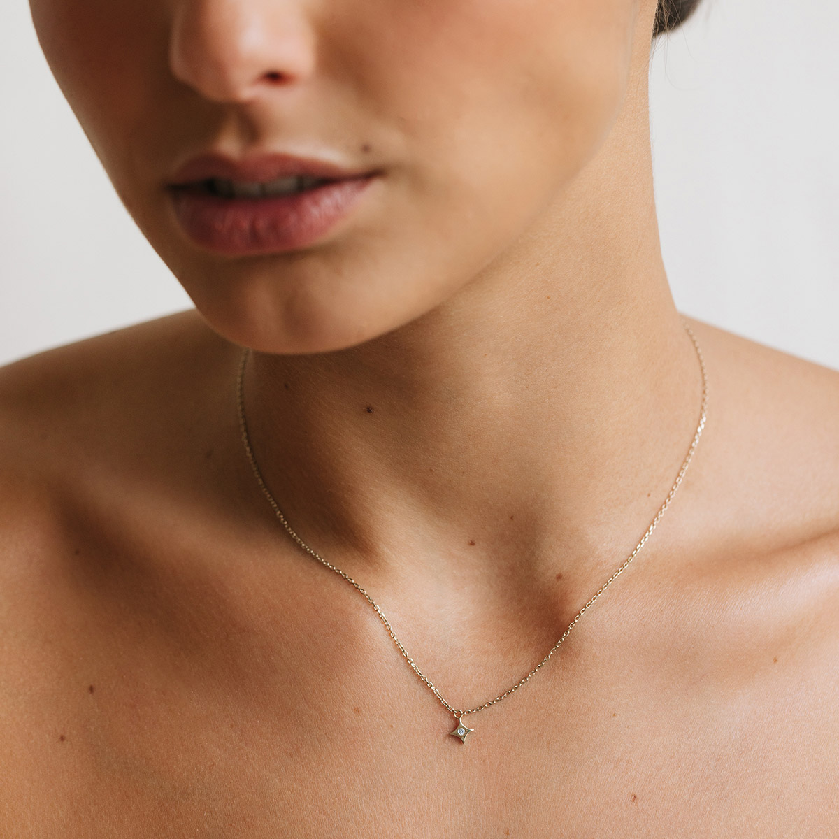 Mulher usando colar feito a mão em ouro 18k com pingente de estrela com diamante no centro minimalista