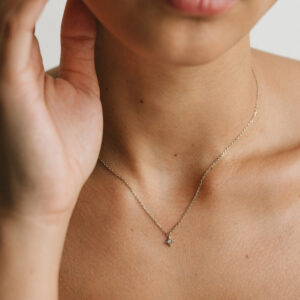 Mulher usando colar feito a mão em ouro 18k com pingente de estrela com diamante no centro minimalista