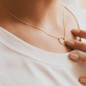 Mulher usando colar feito a mão em ouro 18k com círculo martelado minimalista