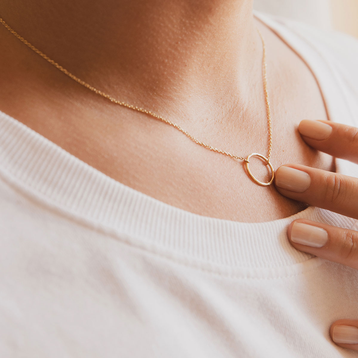 Mulher usando colar feito a mão em ouro 18k com círculo martelado minimalista