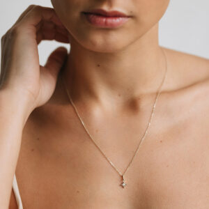 Mulher usando Corrente com pingente minimalista feito a mão em ouro 18k em formato de estrela com diamante no centro