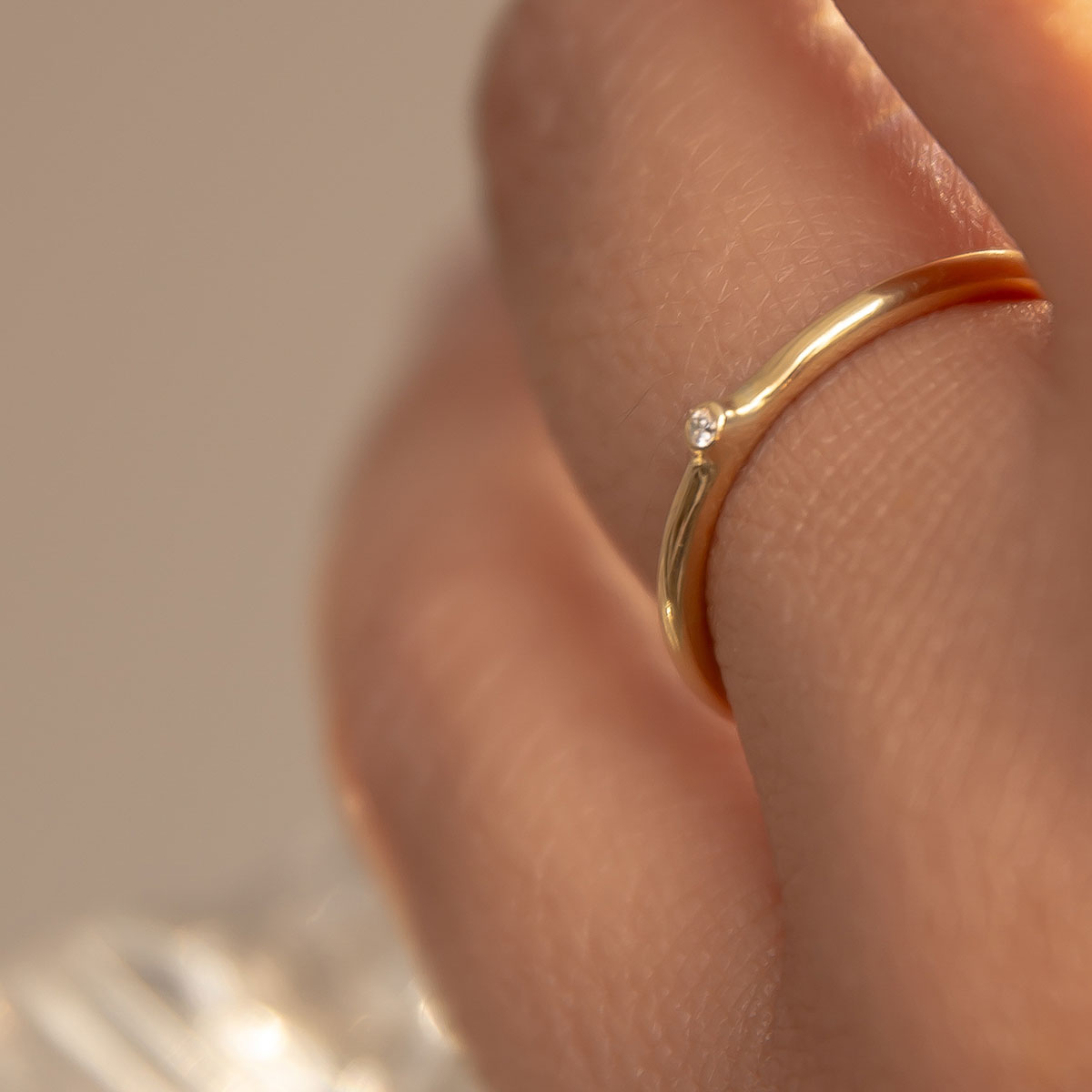 mão feminina usando anel de noivado minimalista de ouro 18k com diamante de 1p feito à mão