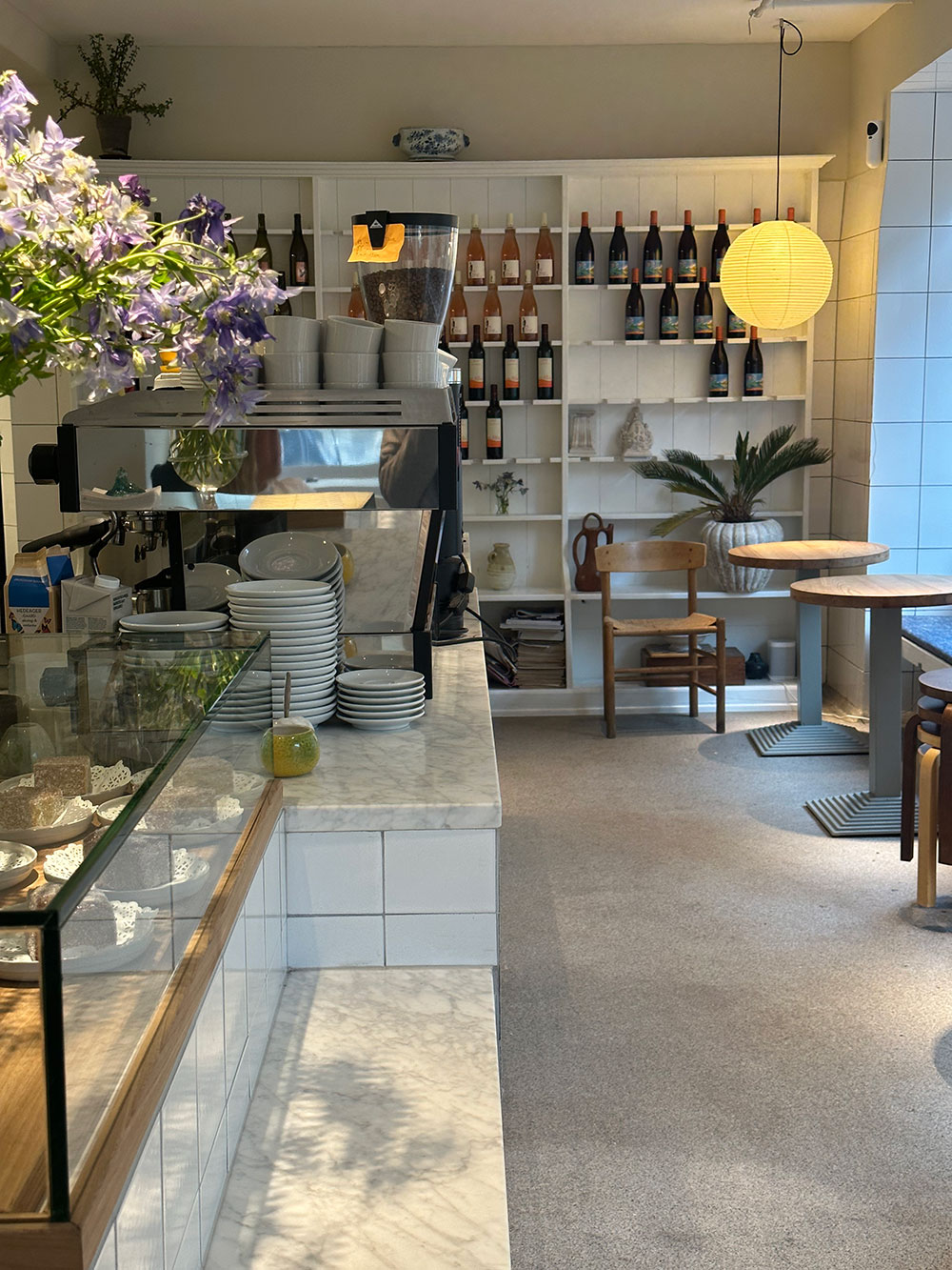 cafeteria bem iluminada com vinhos e mesas pequenas