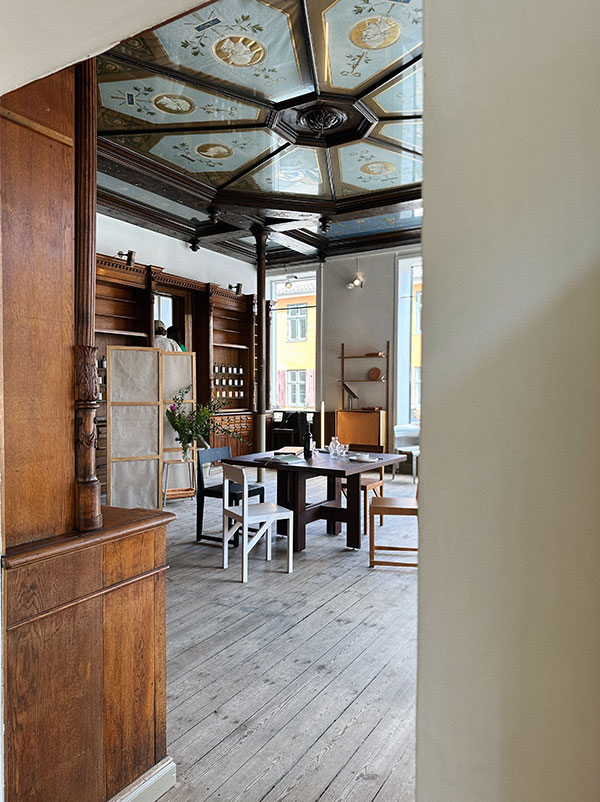 sala com móveis de madeira, teto decorado e mesa quadrada no centro