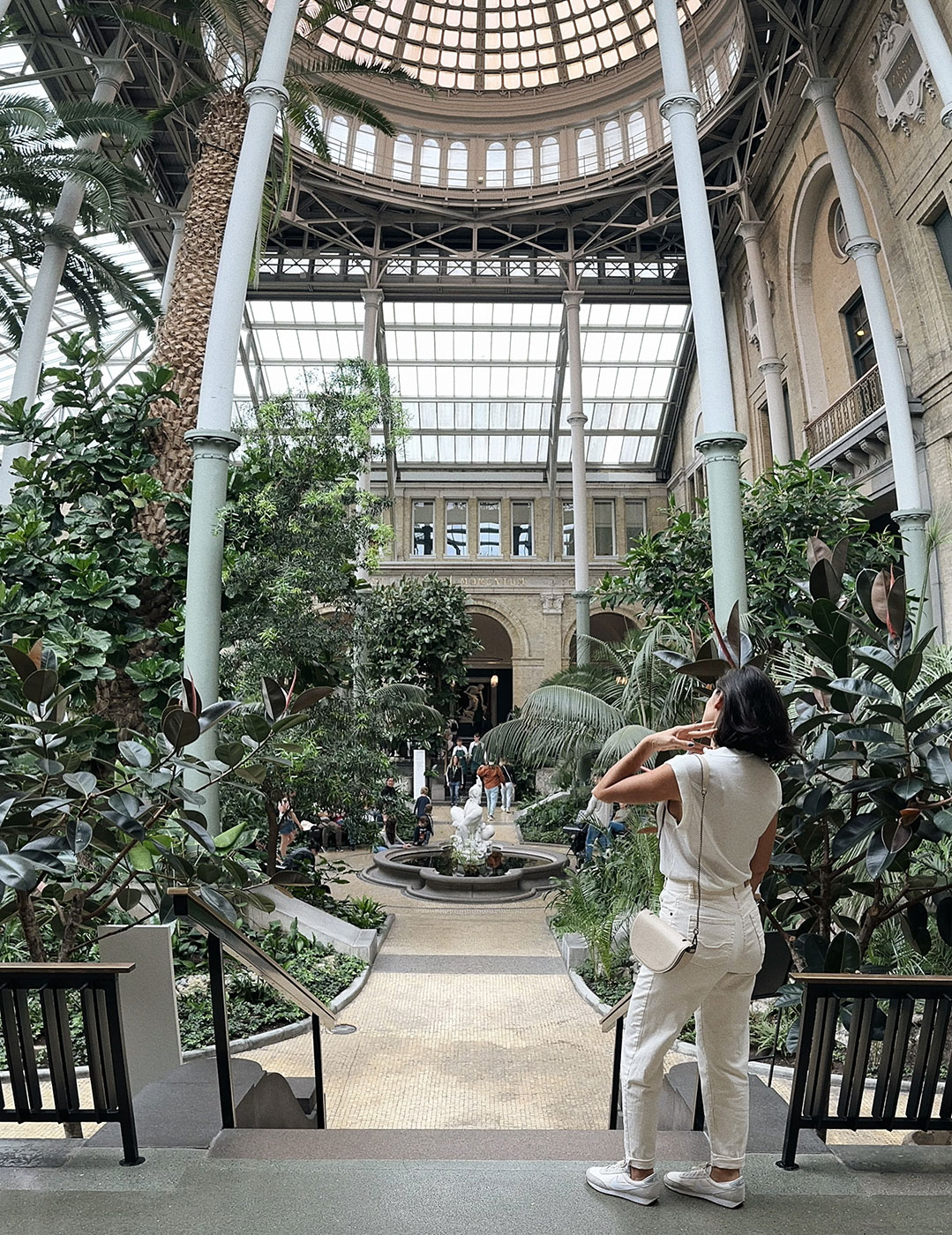 Lie de roupa branca visitando o Glyptoteket, com muitas plantas em destaque